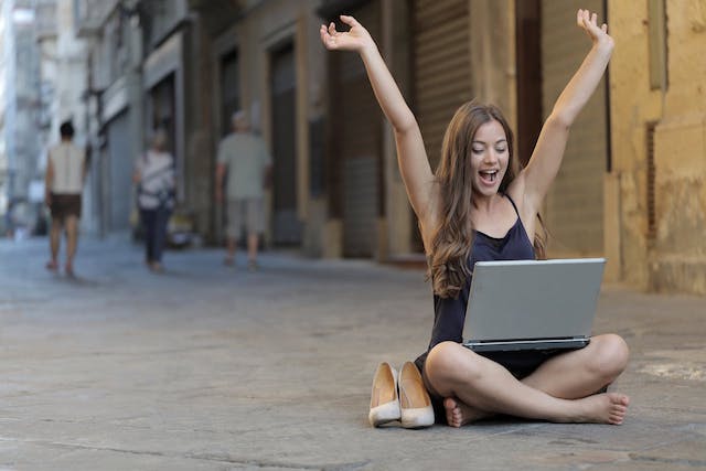 Una chica sentada en la calle sonriendo al recibir un email con su frase inspiradora del día