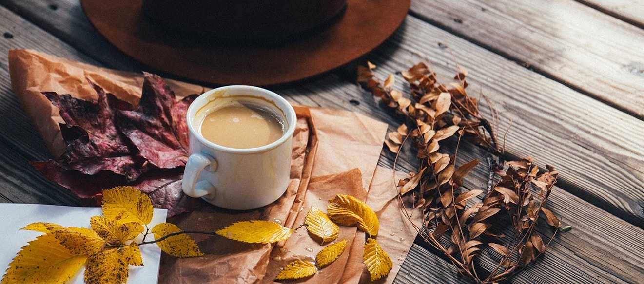 Una taza de café rodeada de hojas secas otoñales, símbolo de inspiración diaria